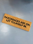 Load image into Gallery viewer, Doormat with 'Razorbacks are on. Let yourself in.' text in a store in Fayetteville, ar Two doormats with Razorbacks are on let yourself in text in a razorback store in Fayetteville, arkansas, razorback door mat, arkansas door mat, razorback welcome mat, Arkansas razorback door mat, razorback front door mat