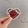 Load image into Gallery viewer, Heart-shaped sticker with a football design and a red logo held by a hand against a gray background, razorback football sticker, razorback sticker, Arkansas razorback stickers near me, razorback shoppe