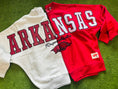 Load image into Gallery viewer, Two sweatshirts, one white and one red, with 'ARKANSAS Razorbacks' text on a grass background. Razorback store in Fayetteville arkansas, arkansas sweatshirts women, university of arkansas crewneck, arkansas razorback store, store near me, Fayetteville ar stores, Arkansas razorback store