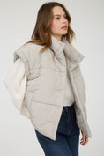 Load image into Gallery viewer, Woman wearing a light gray puffer vest over a white shirt in a Fayetteville, ar clothing store for women, puffer vest, vests for women near me, shopping in fayetteville ar