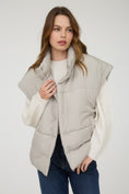 Load image into Gallery viewer, Woman wearing a beige puffer vest over a white shirt in a Fayetteville ar boutiques, clothing store for women, puffer vest, vests for women near me, shopping in fayetteville ar