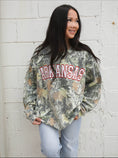 Load image into Gallery viewer, Woman wearing a camouflage Arkansas sweatshirt in Whimsy Whoo Boutique in their Arkansas Razorback Store. Camo Arkansas sweatshirt for women, camo Arkansas shirt, camo arkansas razorback shirt, camo arkansas razorback sweatshirt, camo arkansas crewneck, arkansas razorback store, women Arkansas sweatshirts