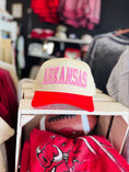 Load image into Gallery viewer, Beige and red cap with 'ARKANSAS' text on a shelf in a Fayetteville, AR Razorback Store. Pink Arkansas hats, pink razorback hats, razorback hats for women, razorback hats near me, Arkansas razorback boutique clothing