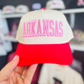 Load image into Gallery viewer, Red and beige cap with 'ARKANSAS' text held by a hand in a Razorback store in Fayetteville, ar. Razorback boutique clothing, Arkansas razorback hat women, pink Arkansas hat, pink razorback hat, women’s razorback hats, women’s Arkansas hats
