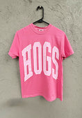 Load image into Gallery viewer, Pink t-shirt with 'HOGS' text on a hanger against a textured wall. Pink hogs shirt, pink razorback shirt, women’s razorback shirt, women’s hogs shirt, razorback shirt for women, hogs shirt for women, razorback top for women, hogs top for women