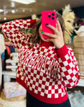 Load image into Gallery viewer, Woman wearing a red and white Razorback checkered sweater , taking a mirror selfie in an arkansas razorback store