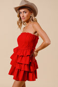 Load image into Gallery viewer, A model wearing a red strapless denim dress with tiered ruffles, paired with white boots and a brown cowboy hat, red strapless dress, red denim dress, red gameday dress, red dress, clothing stores Fayetteville ar