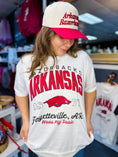 Load image into Gallery viewer, Woman wearing a white t-shirt with Arkansas Razorbacks logo and a matching Razorback cap in a Fayetteville, ar store. Arkansas Razorback store, white women’s razorback shirt, arkansas razorback shirts for women