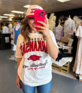 Load image into Gallery viewer, Woman wearing a white t-shirt with razorback graphics, taking a mirror selfie in a Fayetteville store.