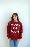 Load image into Gallery viewer, Person wearing a red sweatshirt with 'WOO PIG SOOIE' text in a Fayetteville ar boutique store, Arkansas razorback store, shopping Fayetteville, razorback sweatshirt, arkansas razorback sweatshirt for women