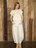 Load image into Gallery viewer, Front view of cream wide-leg denim overalls available for local pickup in NWA or shipping nationwide.