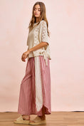 Load image into Gallery viewer, A lifestyle shot of The Free Spirit Striped Barrel Pants in red and white, showing the trendy boho curved-leg silhouette styled for a day out in Fayetteville.