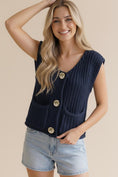 Load image into Gallery viewer, A smiling woman wearing the Life is Golden Button Down Knit Vest in navy blue. This chunky knit vest features three prominent gold buttons and functional front pockets.