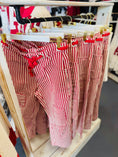 Load image into Gallery viewer, A close-up of red and white striped pull-on barrel pants hanging in a Fayetteville boutique, perfect for an Arkansas Razorback gameday outfit.