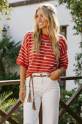 Load image into Gallery viewer, Model wearing the Victory Red Stripe Pullover, a relaxed short-sleeve knit with thin red and white horizontal stripes, styled with denim shorts and turquoise jewelry.