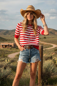 Load image into Gallery viewer, A model wearing the Victory Red Stripe Pullover, a short-sleeve red and white striped knit sweater styled with white jeans and turquoise jewelry for an Arkansas gameday look.