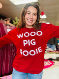 Load image into Gallery viewer, A woman wearing a red Wooo Pig Sooie sweatshirt, highlighting the relaxed fit and bold white "Wooo Pig Sooie" design. You’ll find this in Whimsy Whoo Boutique’s Razorback Store in Fayetteville, AR near the Fayetteville Mall.