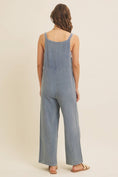 Load image into Gallery viewer, Woman wearing a blue linen-blend jumpsuit on a beige background