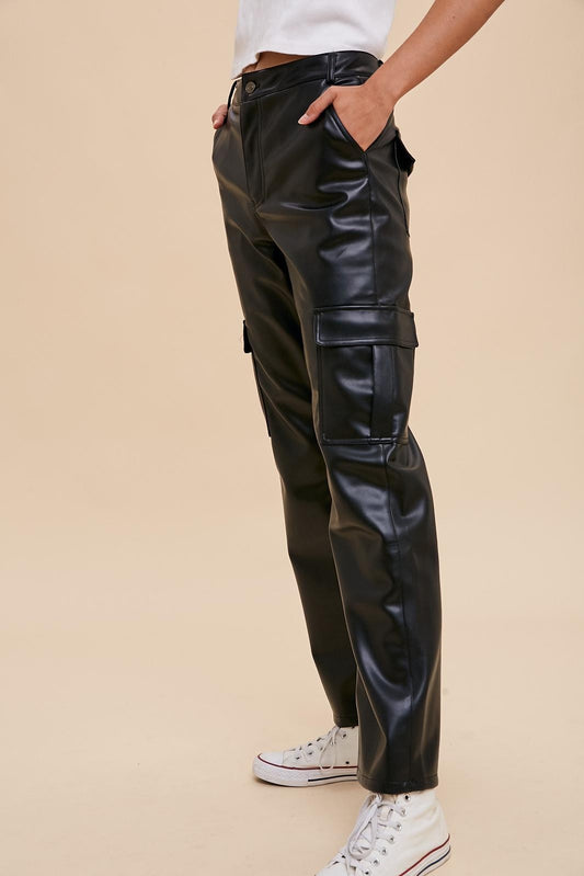 Person wearing black leather cargo pants on a beige background