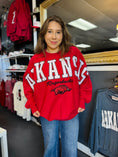 Load image into Gallery viewer, Woman wearing a red 'Arkansas Razorbacks' sweatshirt in a razorback stores in Fayetteville arkansas, Arkansas razorback sweatshirt near me, Arkansas sweatshirt near me, razorback stores in fayetteville
