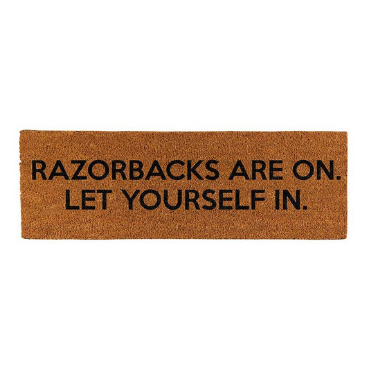 Doormat with text 'RAZORBACKS ARE ON. LET YOURSELF IN.' on a white background