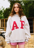 Load image into Gallery viewer, Person wearing a white sweatshirt with red letters and checkered shorts outdoors. red Arkansas reversible sweatshirt, red Arkansas reversible mock neck, Arkansas reversible sweatshirt, Arkansas reversible mock neck, AR reversible sweatshirt, AR reversible mock neck,  red AR reversible sweatshirt, red AR reversible mock neck, store near me, ARkansas reversible mock neck near me, Arkansas reversible sweatshirt near me
