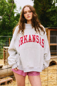 Load image into Gallery viewer, Person wearing a gray sweatshirt with 'ARKANSAS' printed on it, standing outdoors., Arkansas reversible sweatshirt, razorback reversible sweater, Arkansas reversible shirt, Arkansas reversible shirt women’s, razorback store Fayetteville ar, Fayetteville boutiques, shopping near me, boutiques in the NWA mall
