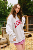Load image into Gallery viewer, Person wearing an 'ARKANSAS' sweatshirt outdoors with trees in the background Arkansas reversible sweatshirt, razorback reversible sweater, Arkansas reversible shirt, Arkansas reversible shirt women’s, razorback store Fayetteville ar, Fayetteville boutiques, shopping near me, boutiques in the NWA mall
