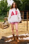 Load image into Gallery viewer, Woman wearing a white sweatshirt with 'AP' letters, pink shorts, and brown boots in an outdoor setting. Arkansas reversible sweatshirt, razorback reversible sweater, Arkansas reversible shirt, Arkansas reversible shirt women’s, razorback store Fayetteville ar, Fayetteville boutiques, shopping near me, boutiques in the NWA mall
