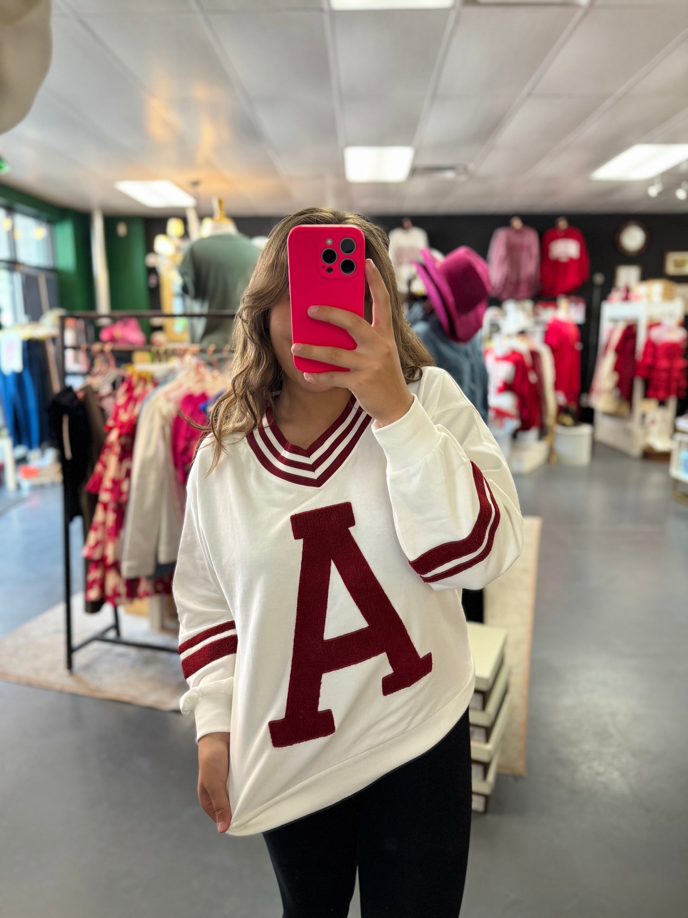 Person wearing a white sweater with a red 'A' in a clothing store. Vintage Arkansas sweatshirt, Arkansas sweatshirt women, Arkansas sweatshirt near me, Arkansas sweatshirt nearby, Arkansas sweatshirt blanket