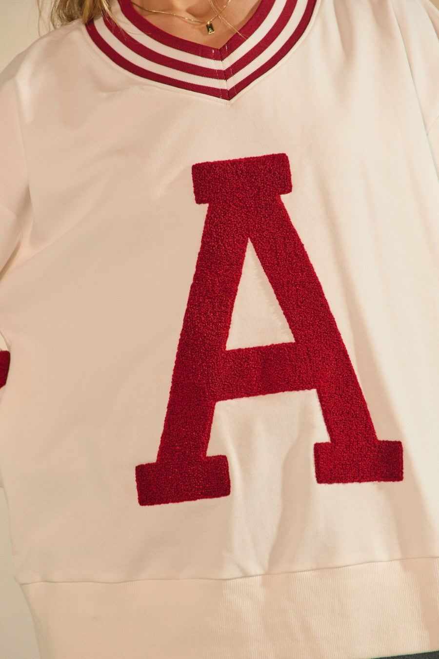 Beige sweater with a large red letter 'A' on a neutral background Arkansas varsity style sweatshirt, sweatshirt with an arkansas “A”, raorback sweatshirt, white Arkansas sweatshirt, shopping in Fayetteville, ar, razorback store near me