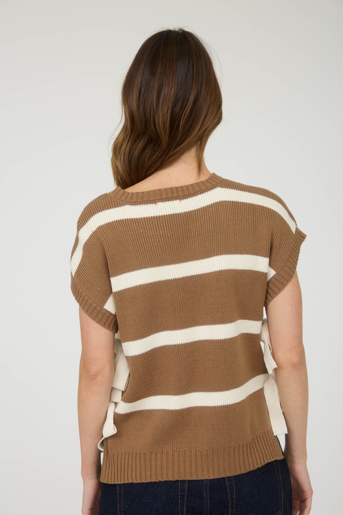 Woman wearing a brown and white striped sleeveless sweater against a plain background, weater, sweater vest, sweaters for women, sweater vest women, sweater women, knit sweater, oversized sweaters, clothing store near me