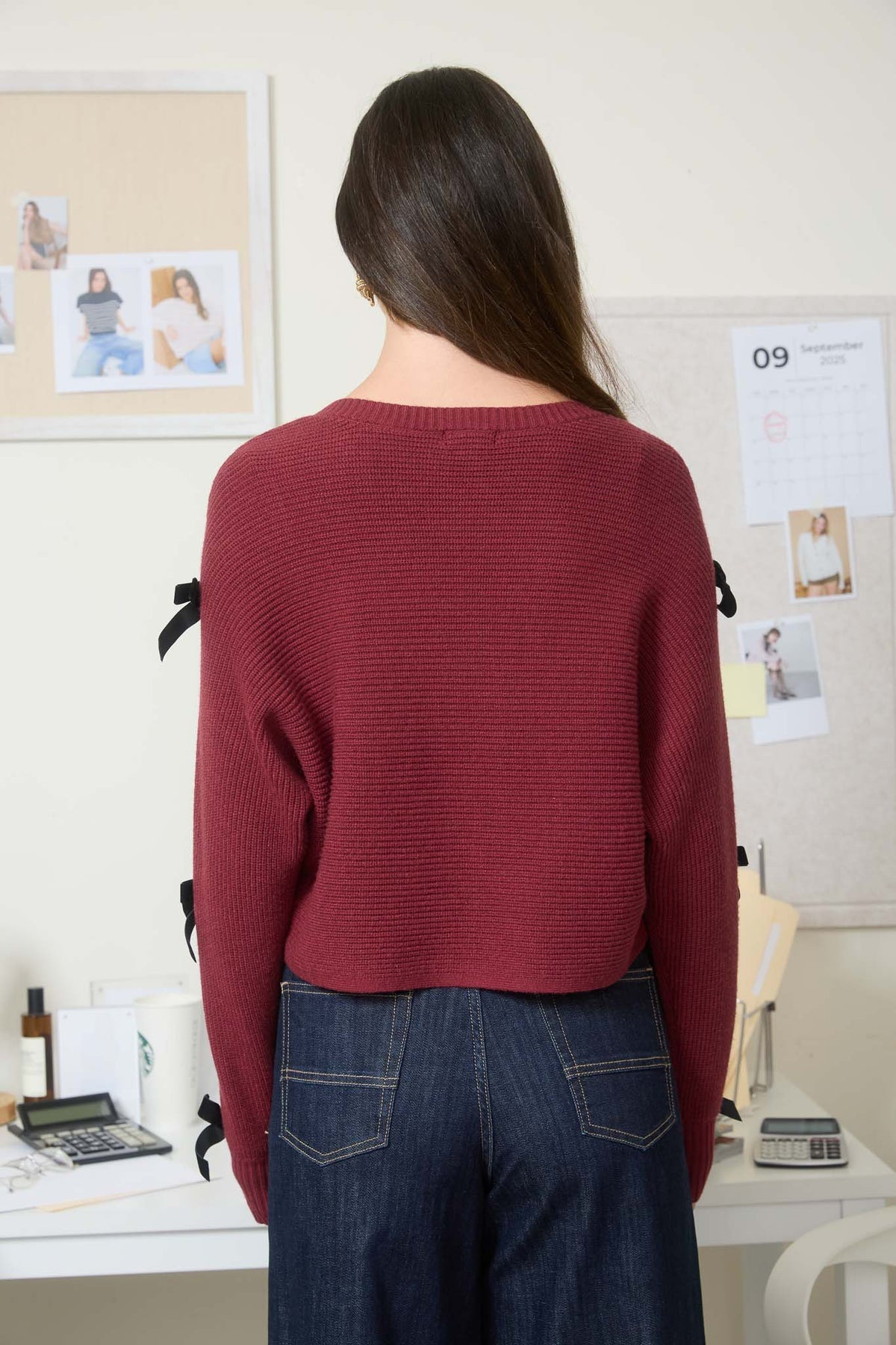 Person wearing a red sweater and blue jeans standing in a boutique in Fayetteville ar, Sweater, sweaters for women, knit sweater, clothing stores in Fayetteville ar