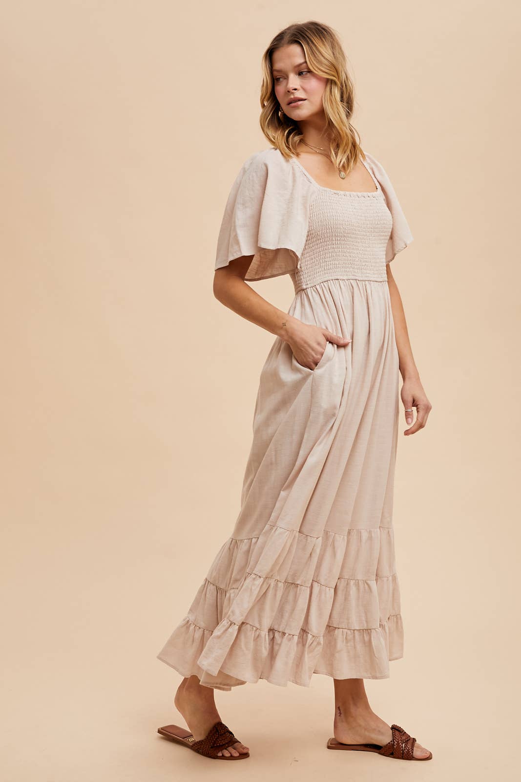 Woman wearing a beige dress with a matching cardigan against a beige background, beige dress, beige smocked dress, fall dresses, dresses for fall, wedding guest dress, fall wedding guest dress