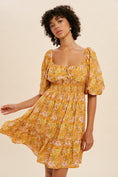 Load image into Gallery viewer, Woman wearing a yellow floral dress against a beige background
