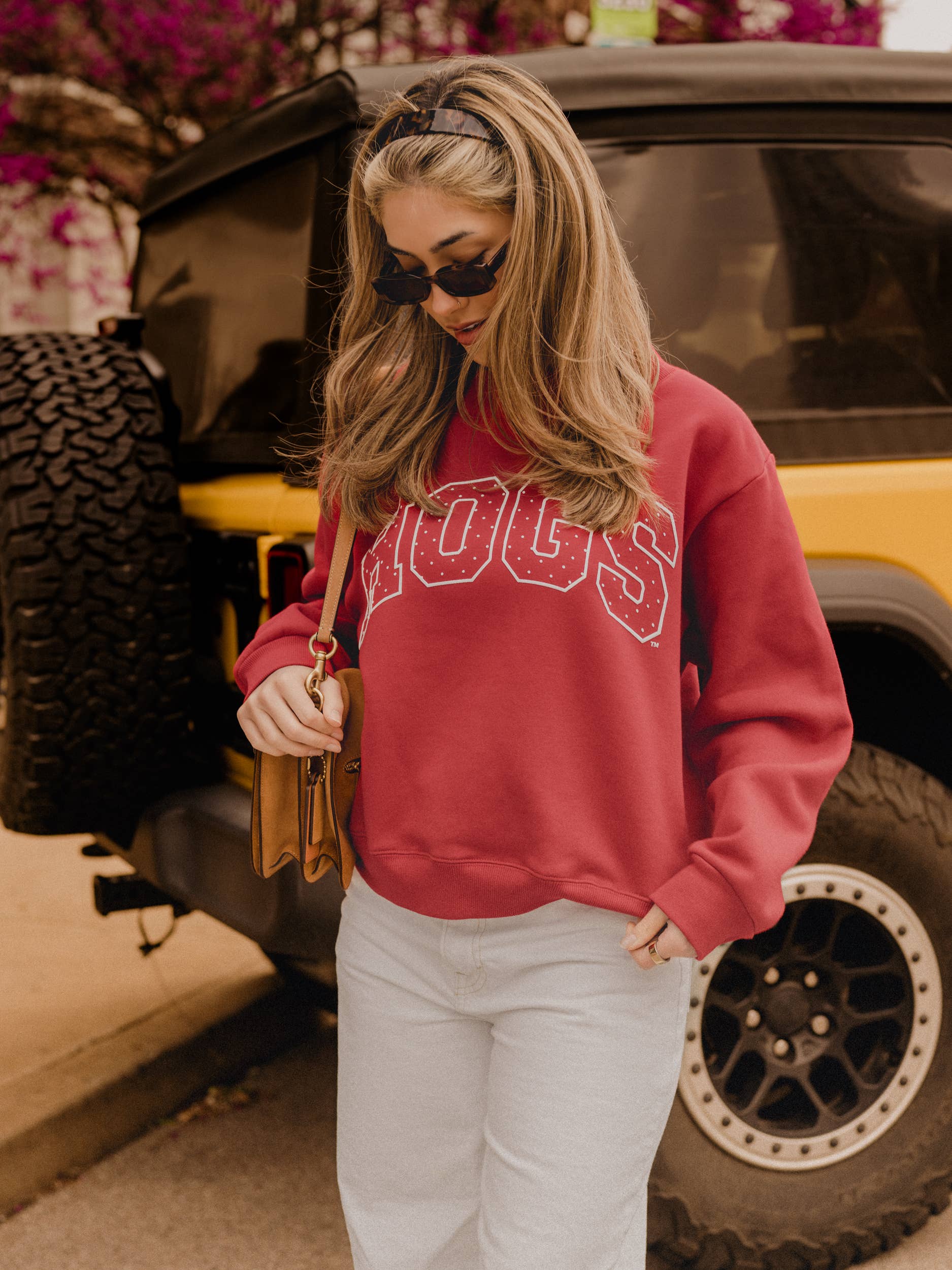 Woman wearing a red sweatshirt with 'HOGS' printed on it, standing next to a yellow vehicle.