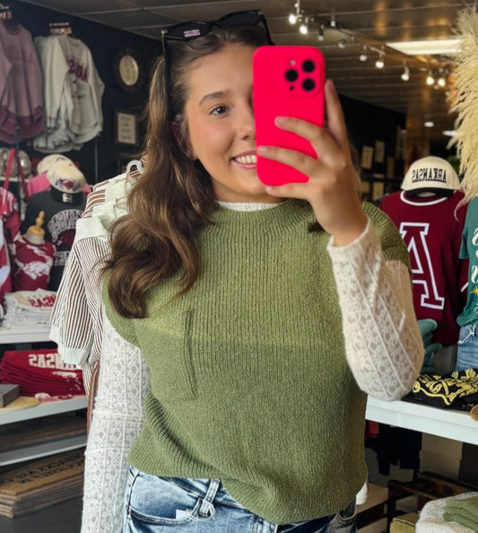 Women  taking a selfie in a Fayetteville ar boutique store wearing a green sweater vest and holding a pink phone case. Green sweater, green short sleeve sweater, blu pepper sweater, boutiques near me, boutiques Fayetteville ar