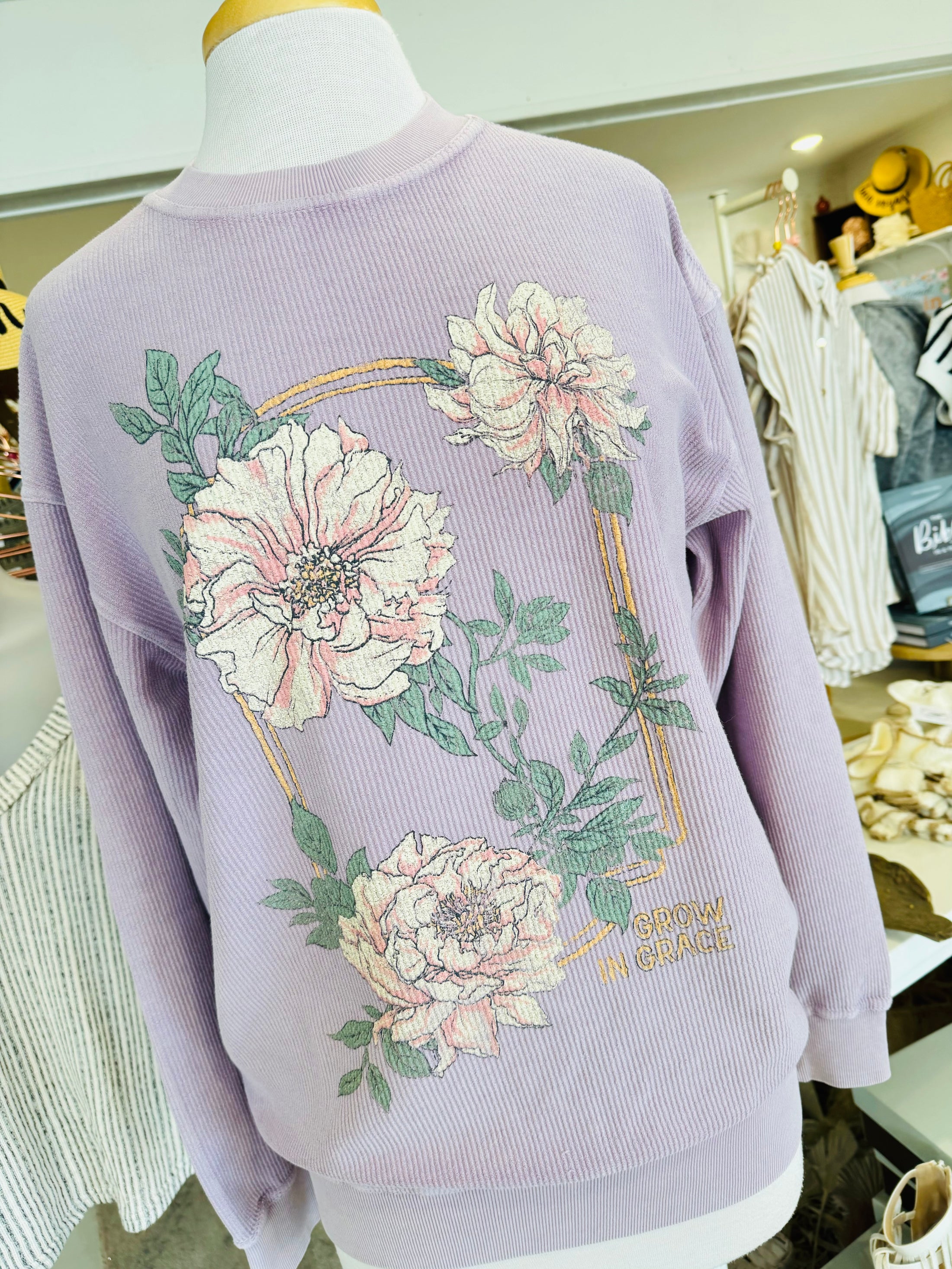 Lavender sweater with floral designs on a mannequin in a store setting