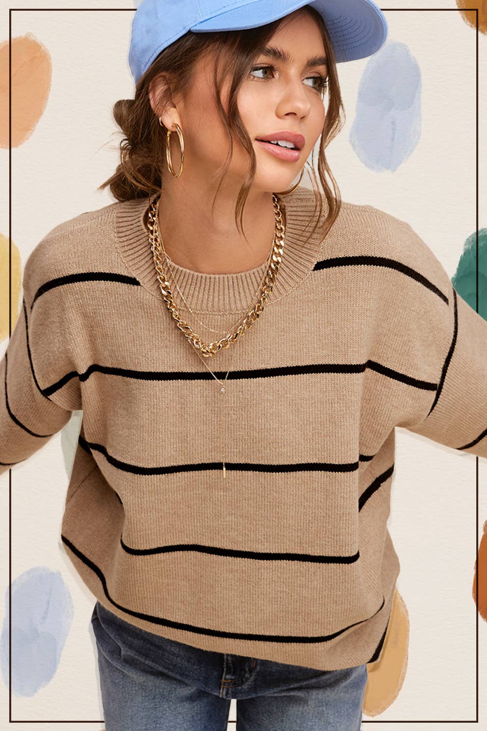 Woman wearing a beige sweater with black stripes, blue jeans, and a blue cap against a polka dot background. Clothing stores Fayetteville ar, la miel clothing, women’s sweaters, Whimsy woo