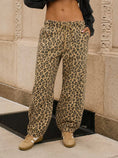 Load image into Gallery viewer, A woman wearing loose leopard-print drawstring pants, paired with beige sneakers and a dark cropped top, from Whimsy Whoo boutique in Fayetteville, AR
