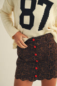 Load image into Gallery viewer, Person wearing a cream sweater with large black numbers and a leopard print skirt with red buttons. Fayetteville ar boutique store
