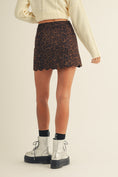 Load image into Gallery viewer, Woman wearing a leopard print skirt and white boots on a beige background
