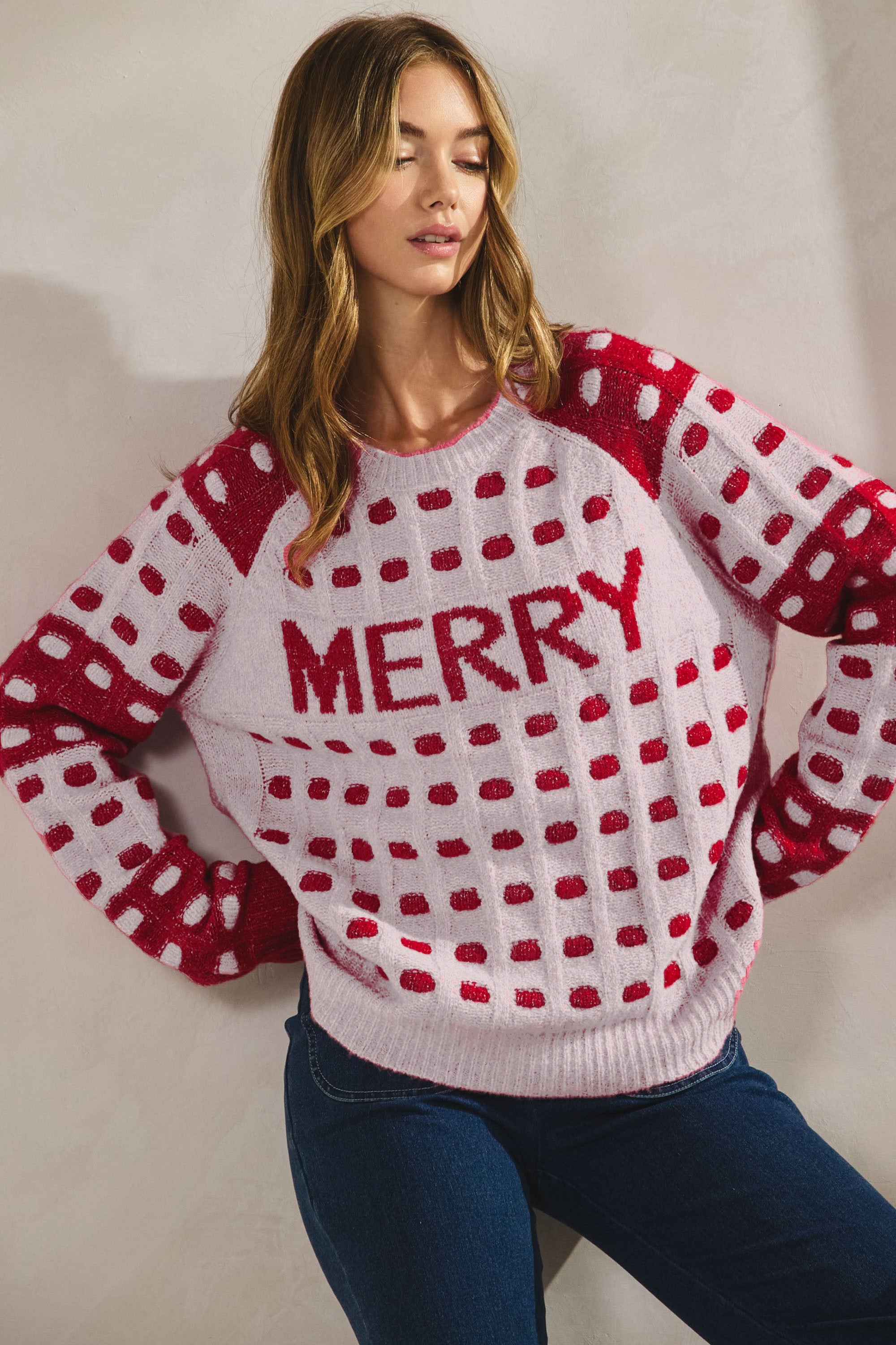 Woman wearing a red and white sweater with 'MERRY' graphic in a Fayetteville, ar store, christmas sweaters for women, christmas sweaters and sweatshirts for women, shopping Fayetteville ar