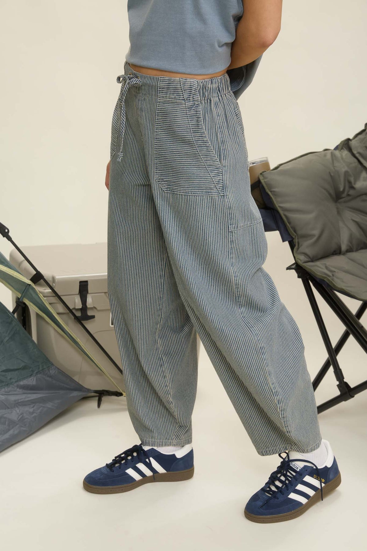 Person wearing gray checkered pants and blue Adidas sneakers in a minimal indoor setting. navy parachute pants, parachute pants 80s, parachute pants women, parachute pants h&m, parachute pants 90s, parachute pants near me, parachute pants my hammer, barrel pants, barrel leg pants, barrel jeans barrel pants trousers, barrel jeans women, barrel pants anthropology