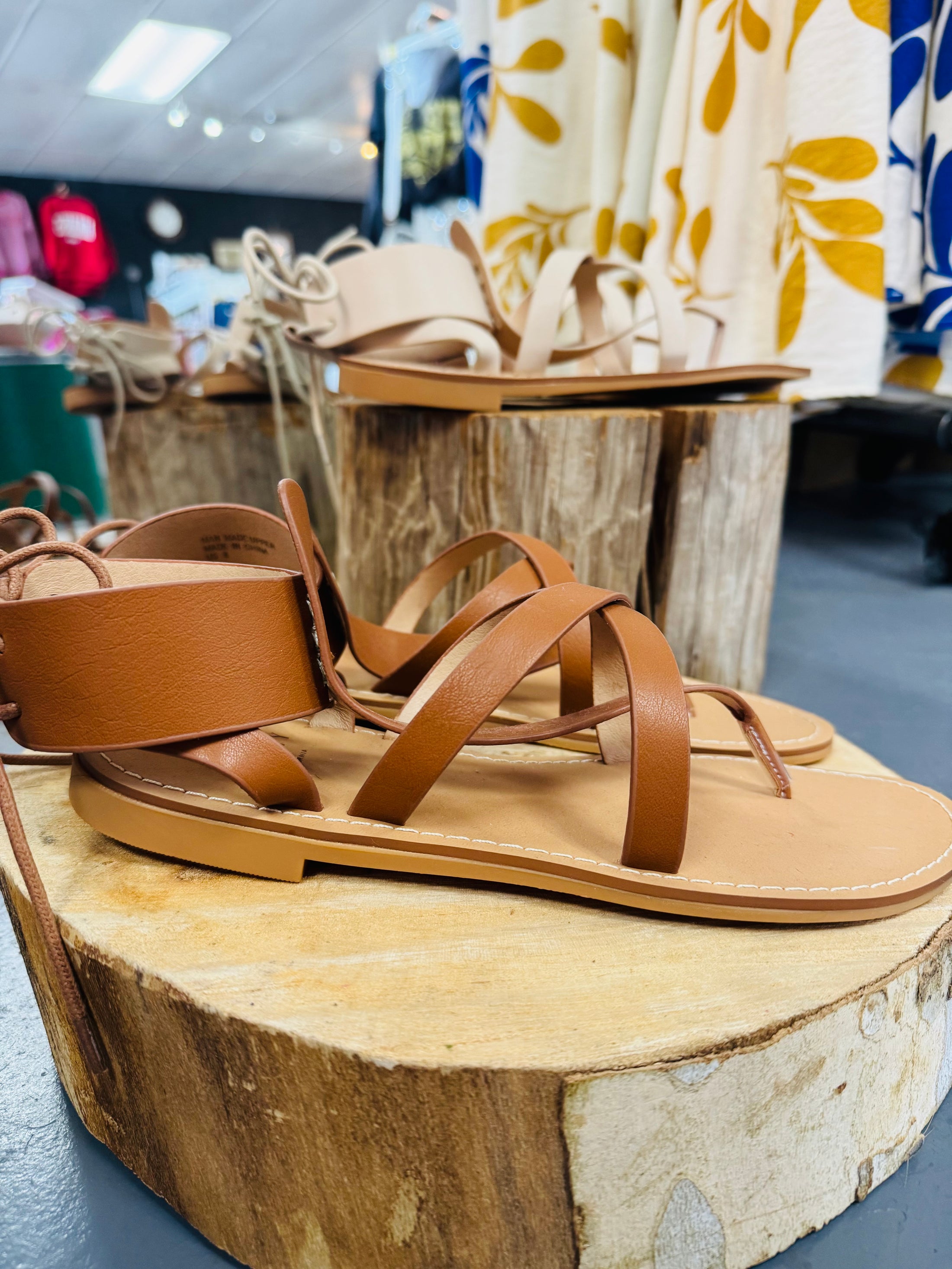 Brown sandals on a wooden block with a store setting in the background, oasis society sandals, shoes in Fayetteville arkansas, boutique in Fayetteville arkansas, beige sandals, sandals on sale