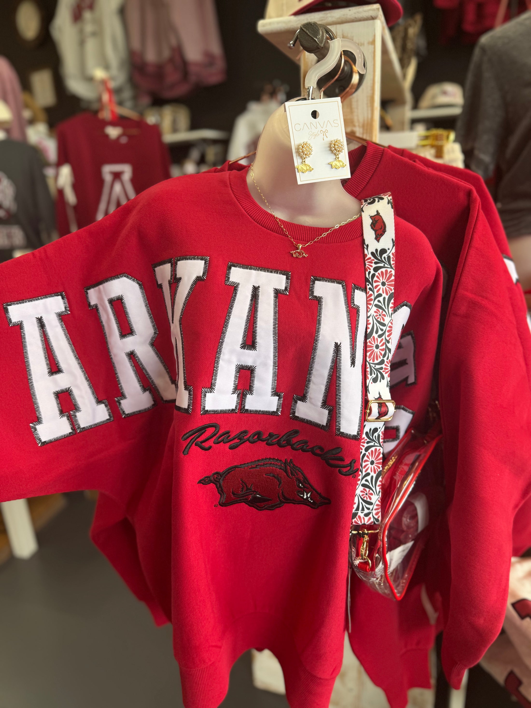 Red sweatshirt with 'ARKANSAS Razorbacks' text and logo on a mannequin in a Fayetteville ar razorback shoppe, boutique near me, razorback shopping near me