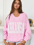 Load image into Gallery viewer, Woman wearing a pink sweater with 'ARKANSAS' printed on it against a white background, arkansas sweatshirt, A sweatshirt, arkansas sweatshirt women, arkansas sweatshirt near me, arkansas sweatshirt nearby, embroidered arkansas sweatshirt, university of arkansas crewneck, pink arkansas shirt, pink arkansas sweatshirt
