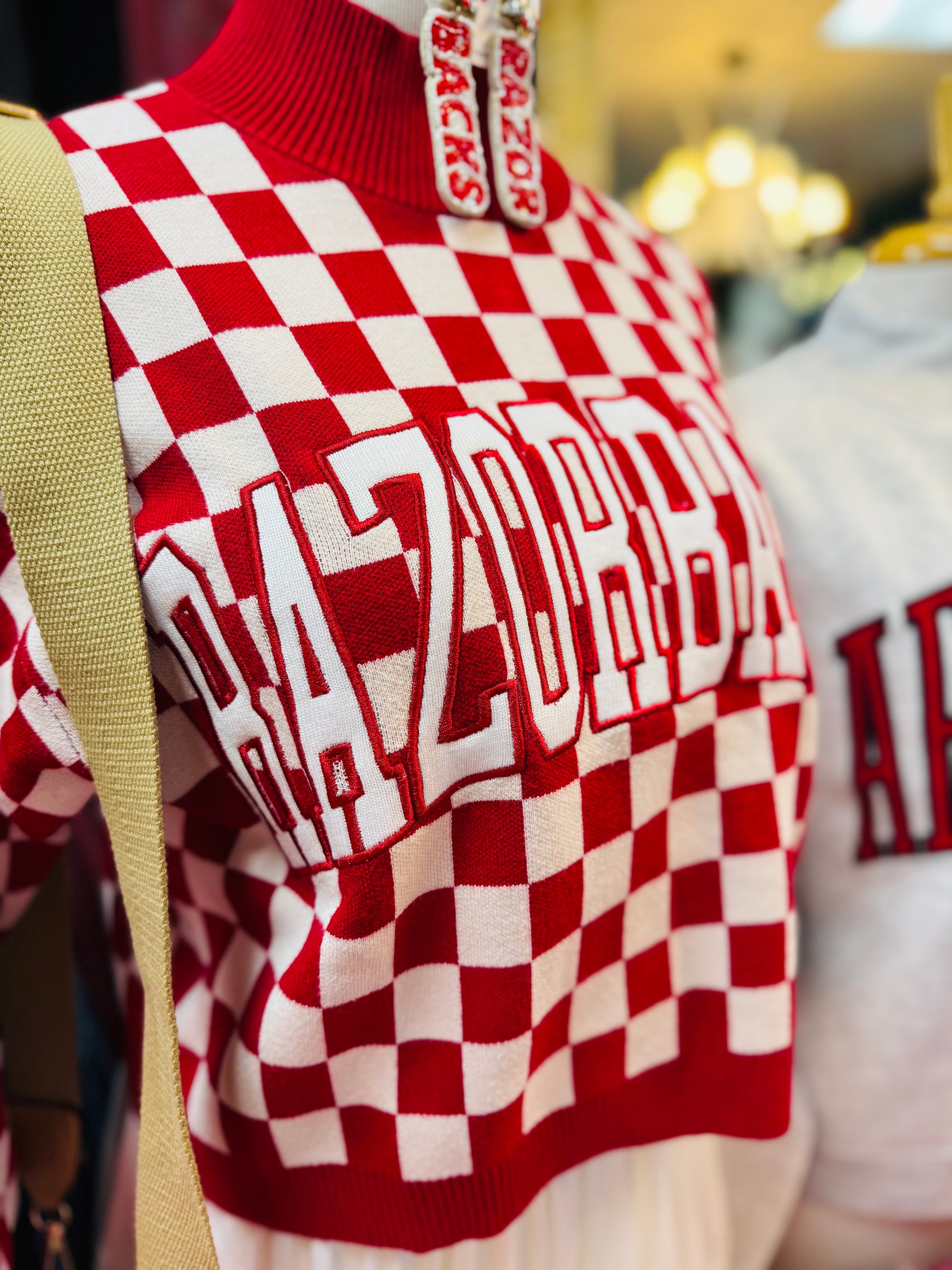 Red and white checkered sweater with Razorback branding and Arkansas Razorback accessories, beaded earrings, in an Arkansas Razorback Store in Fayetteville, AR