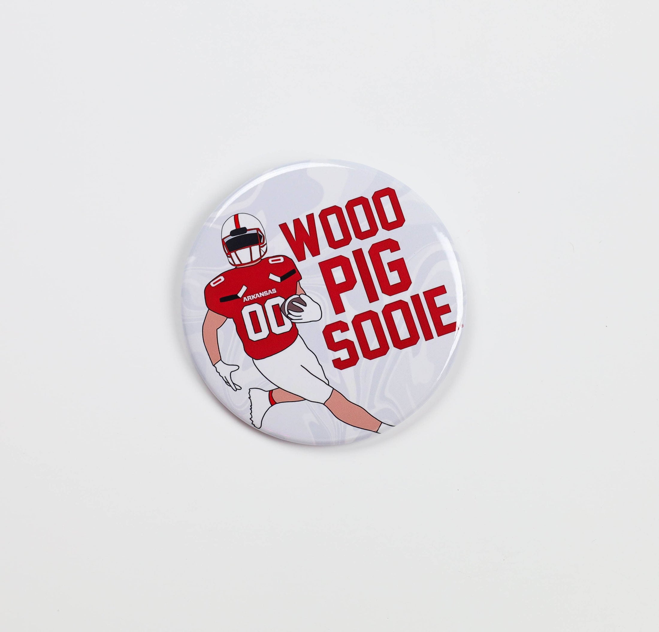 Button badge with football player graphic and 'Wood Pig Sooie' text on a white background, arkansas razorback jewelry and accessories, boutiques open now, razorback store Fayetteville ar