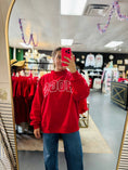 Load image into Gallery viewer, A person taking a mirror selfie in a clothing store, wearing a bright red sweatshirt with 'HOGS' printed in white across the chest and blue jeans.

